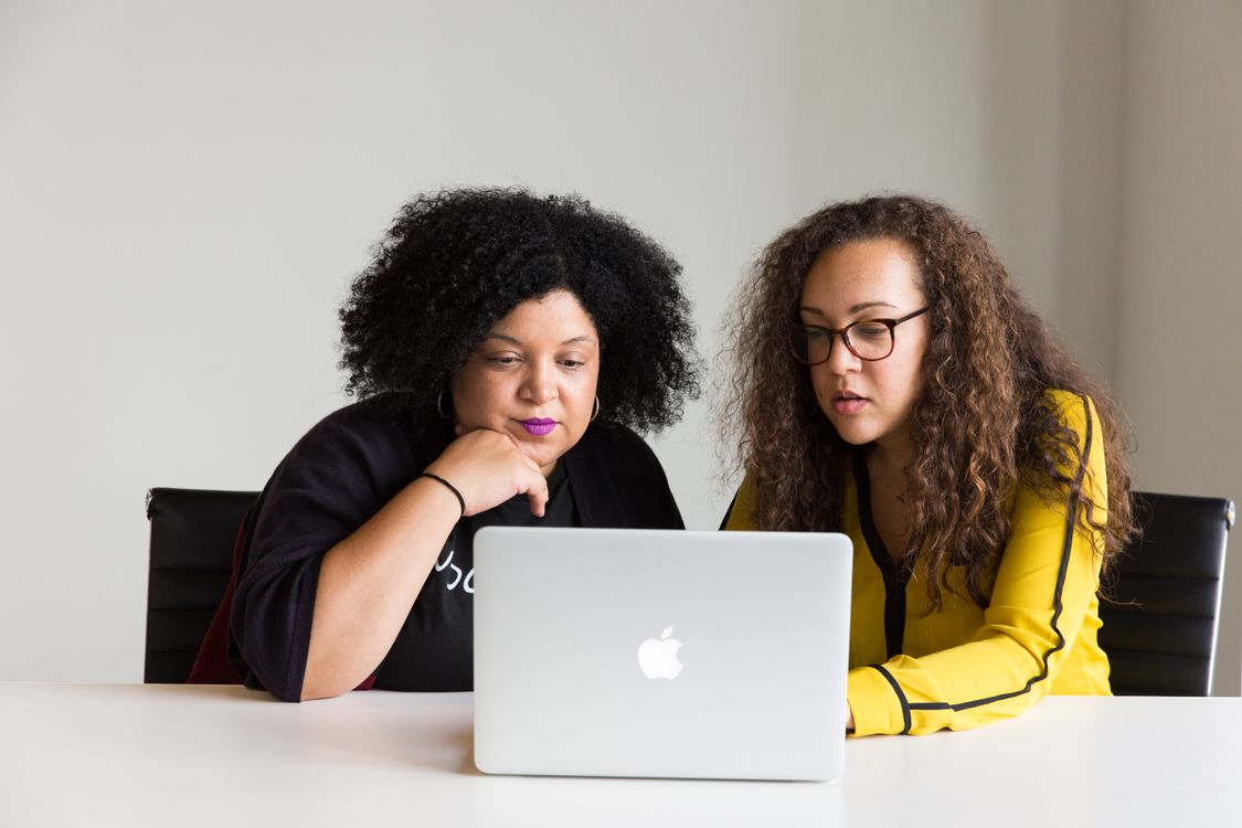 Two colleagues reviewing information together on a laptop